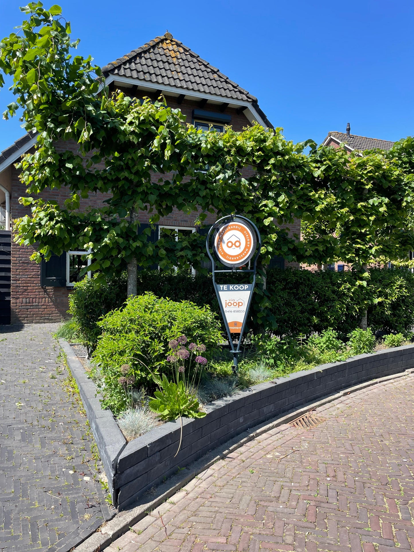 Draaiend makelaarsbord van ViaJoop die in de tuin staat als Verkocht