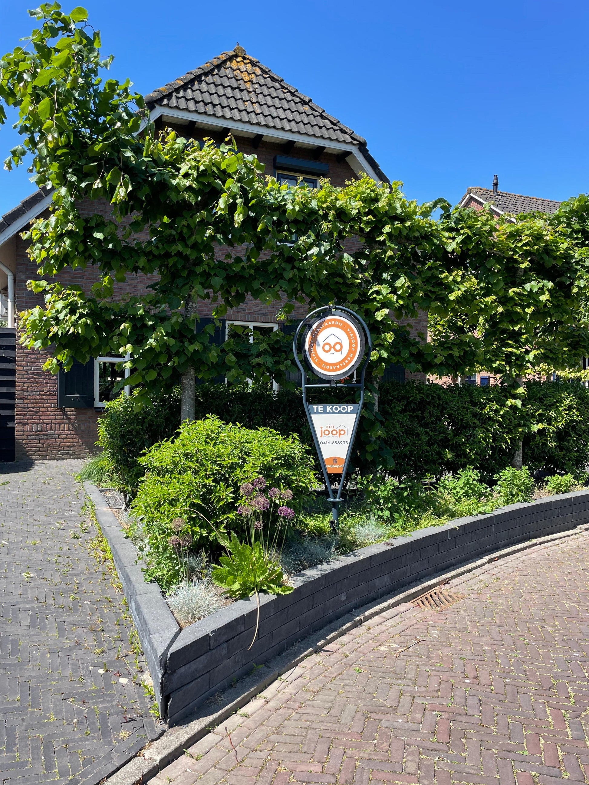 Draaiend makelaarsbord van ViaJoop die in de tuin staat als Verkocht