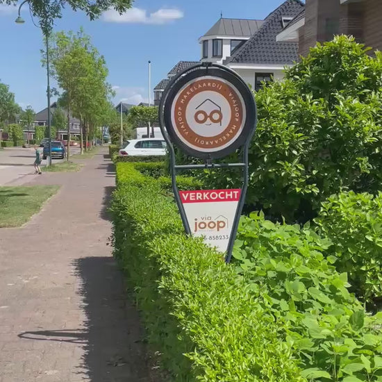 Draaiend makelaarsbord van ViaJoop die in de tuin staat als Verkocht