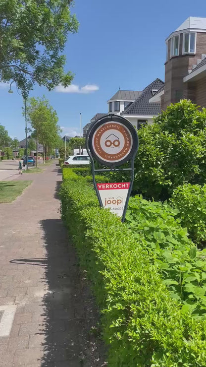 Draaiend makelaarsbord van ViaJoop die in de tuin staat als Verkocht