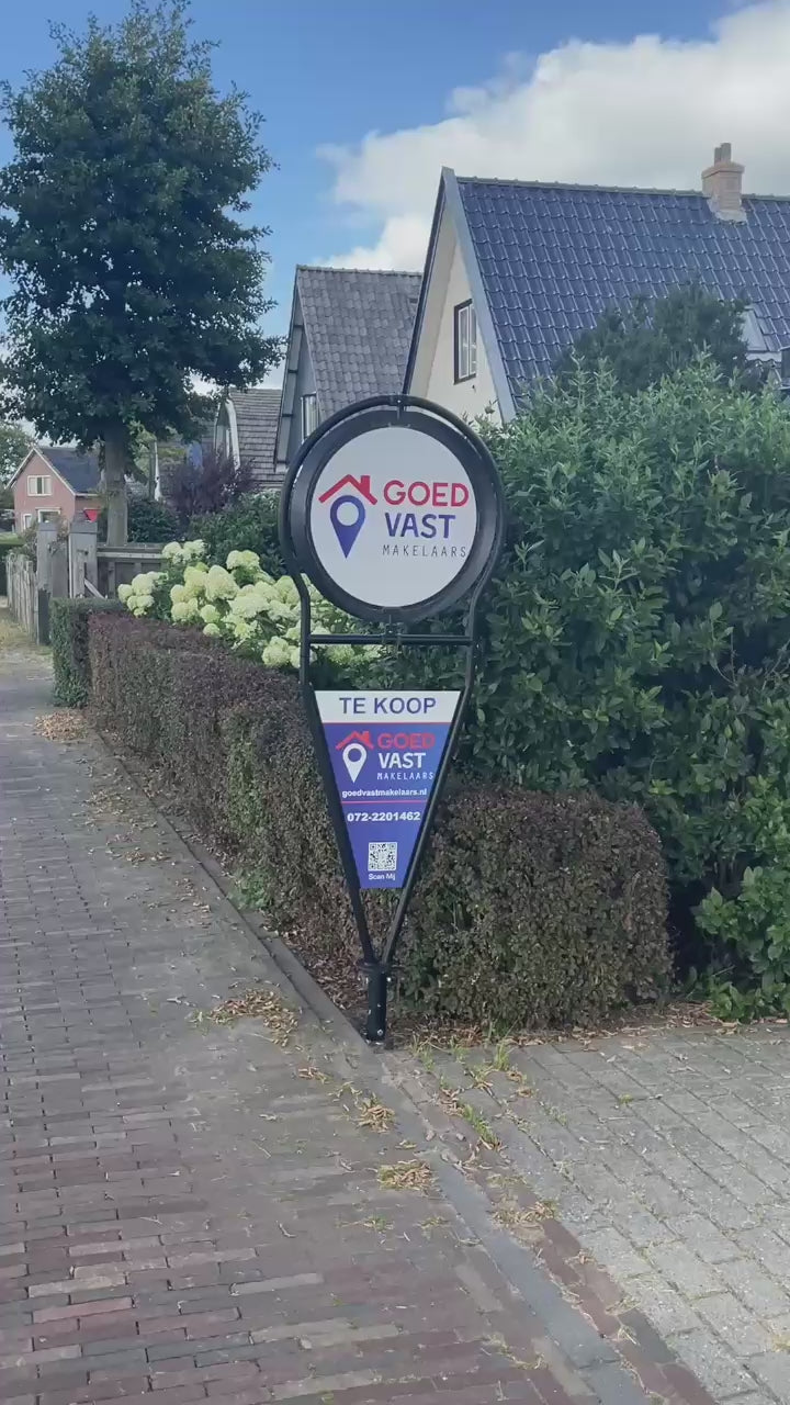 Draaiend makelaarsbord van GoedVast Makelaars die in de tuin staat als Te Koop