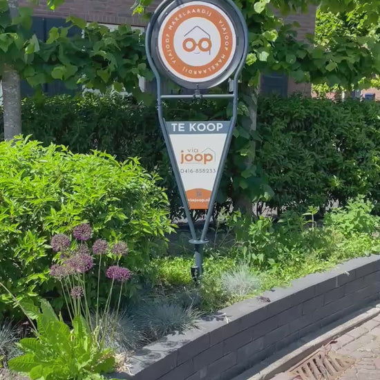 Draaiend makelaarsbord van ViaJoop die in de tuin staat als Te Koop