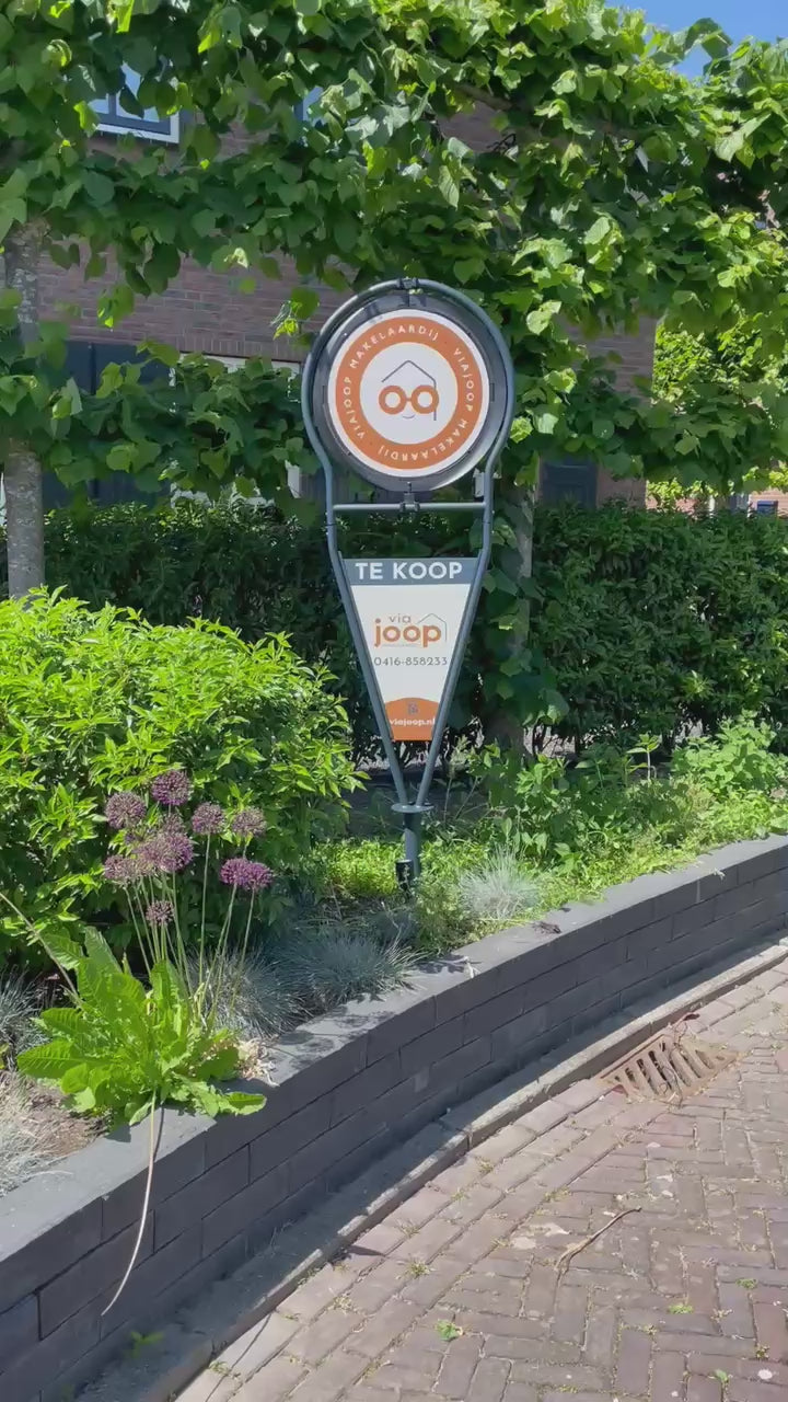 Draaiend makelaarsbord van ViaJoop die in de tuin staat als Te Koop