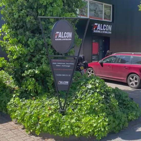 Draaiend reclamebord van Falcon die voor zijn Rijschool staat